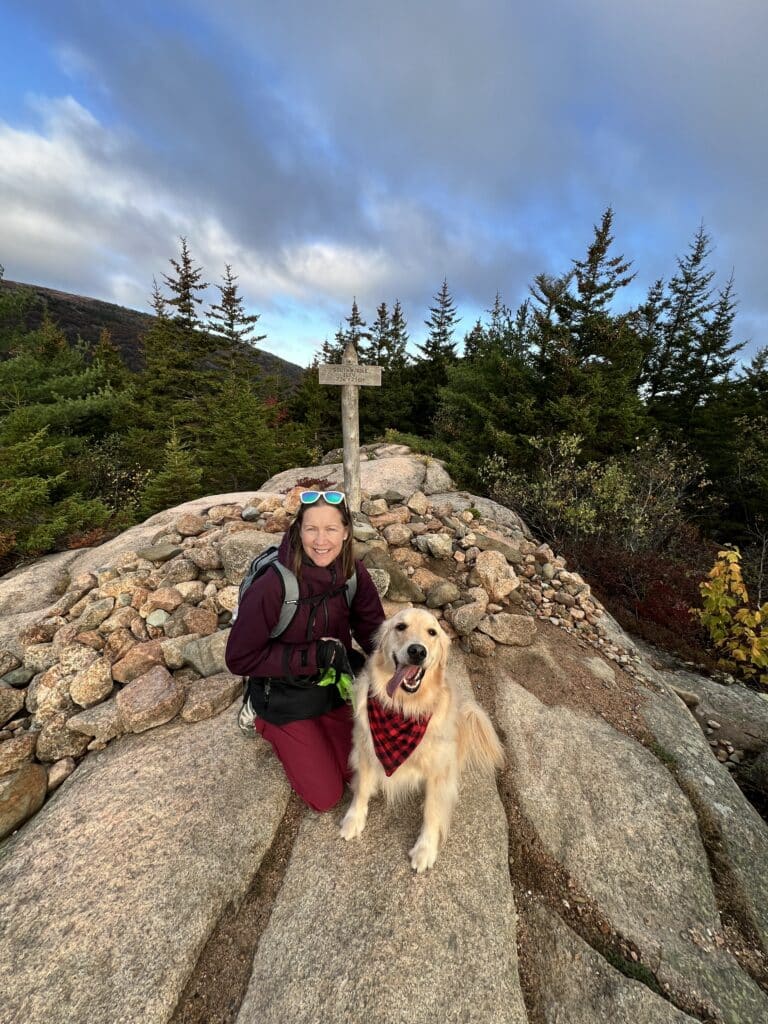 Female and Golden Retriever at mountain Summit at Acadia National Park