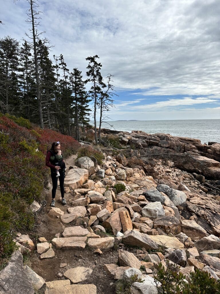 Picture of Female with baby in front carrier on rocky trail on coast of Acadia National Park