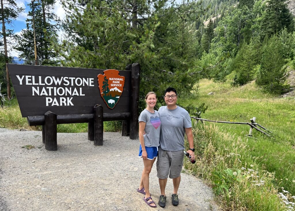 Yellowstone National Park entrance sign with male and female standing in front